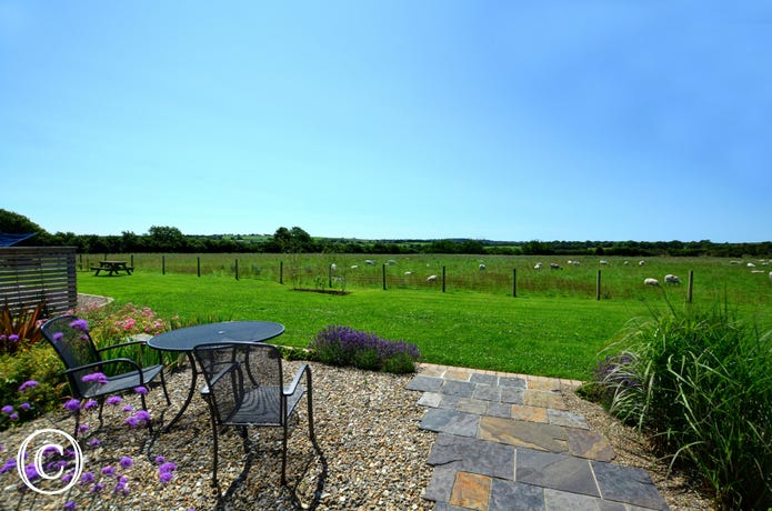 Small patio area to the rear of the cottage with garden furniture and views across farmland