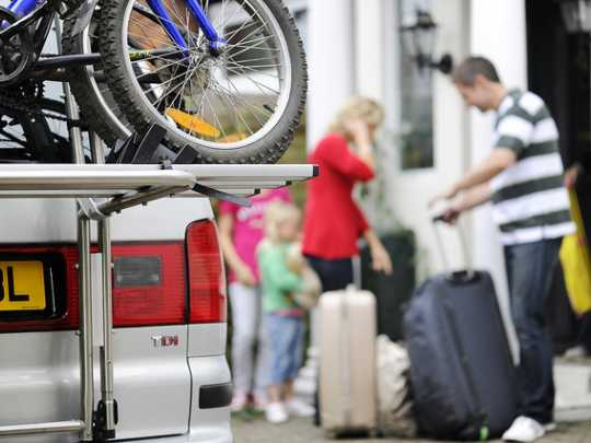 Family with suitcases and a car with bicycles